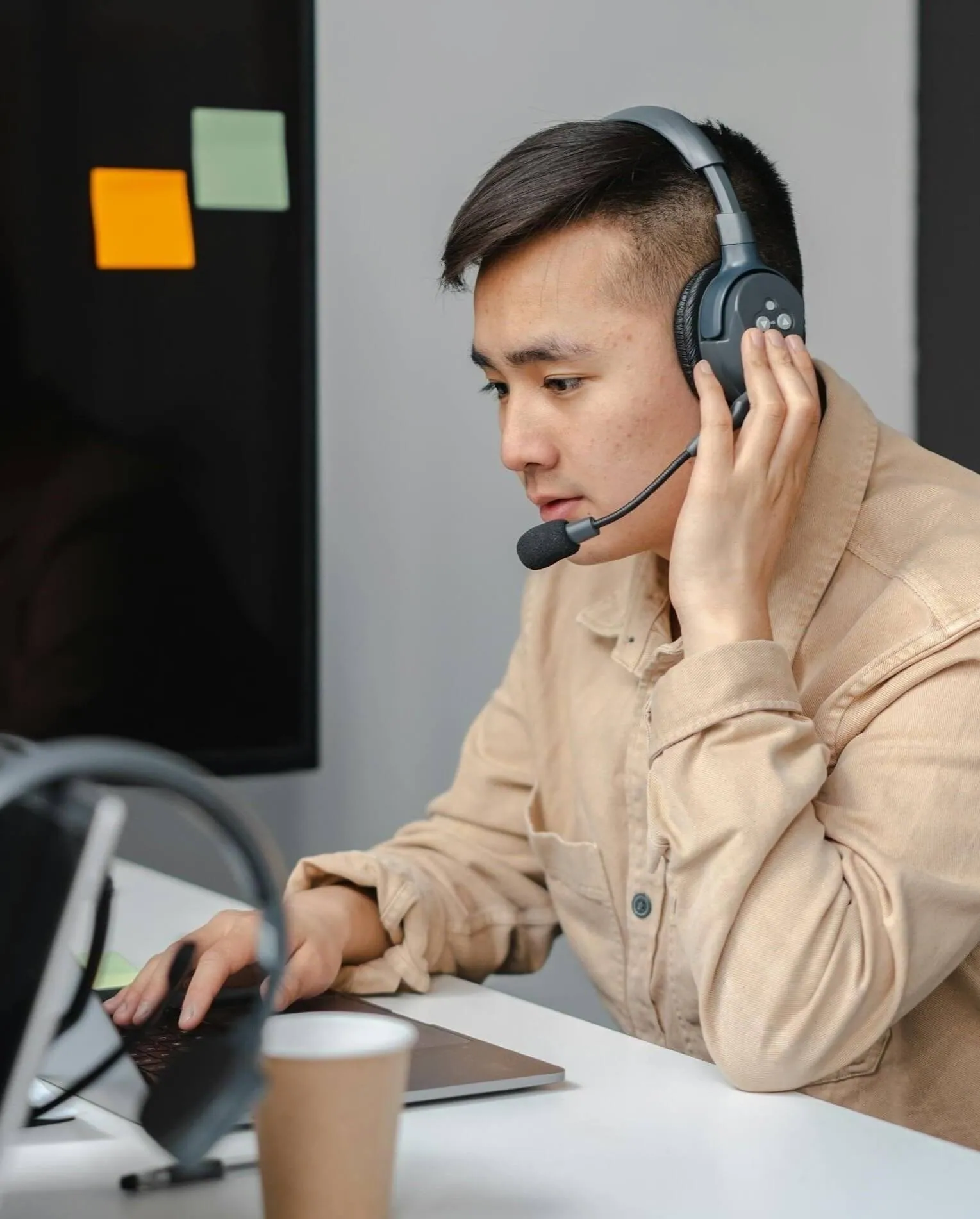 Man talking on a headset while typing on a laptop