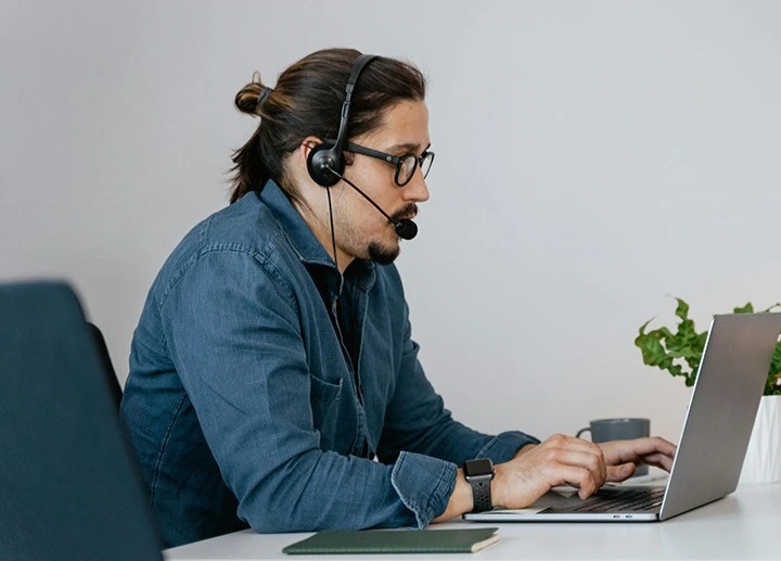 Man wearing a headset and typing on a laptop