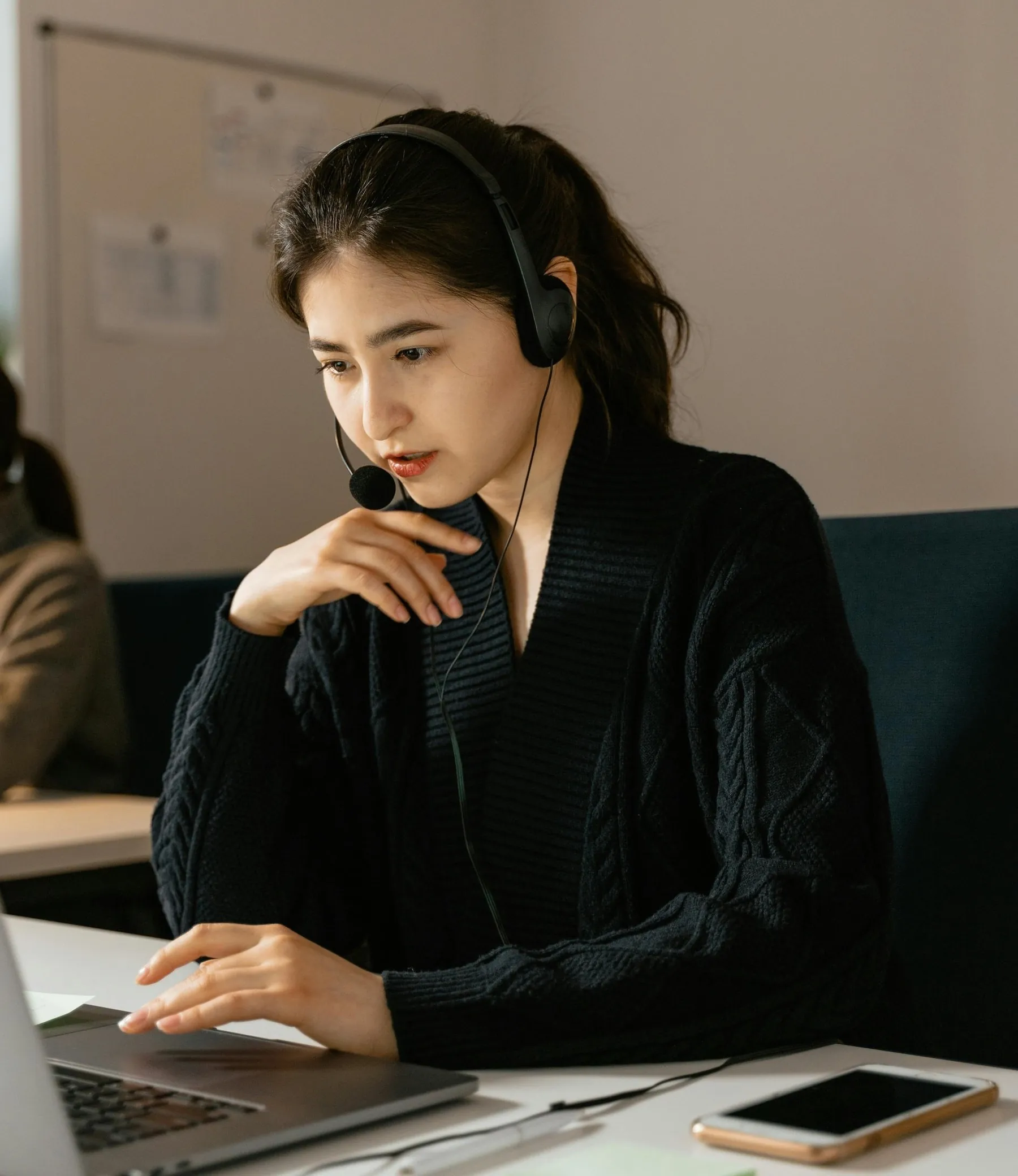 Woman talking on a headset while working on a laptop